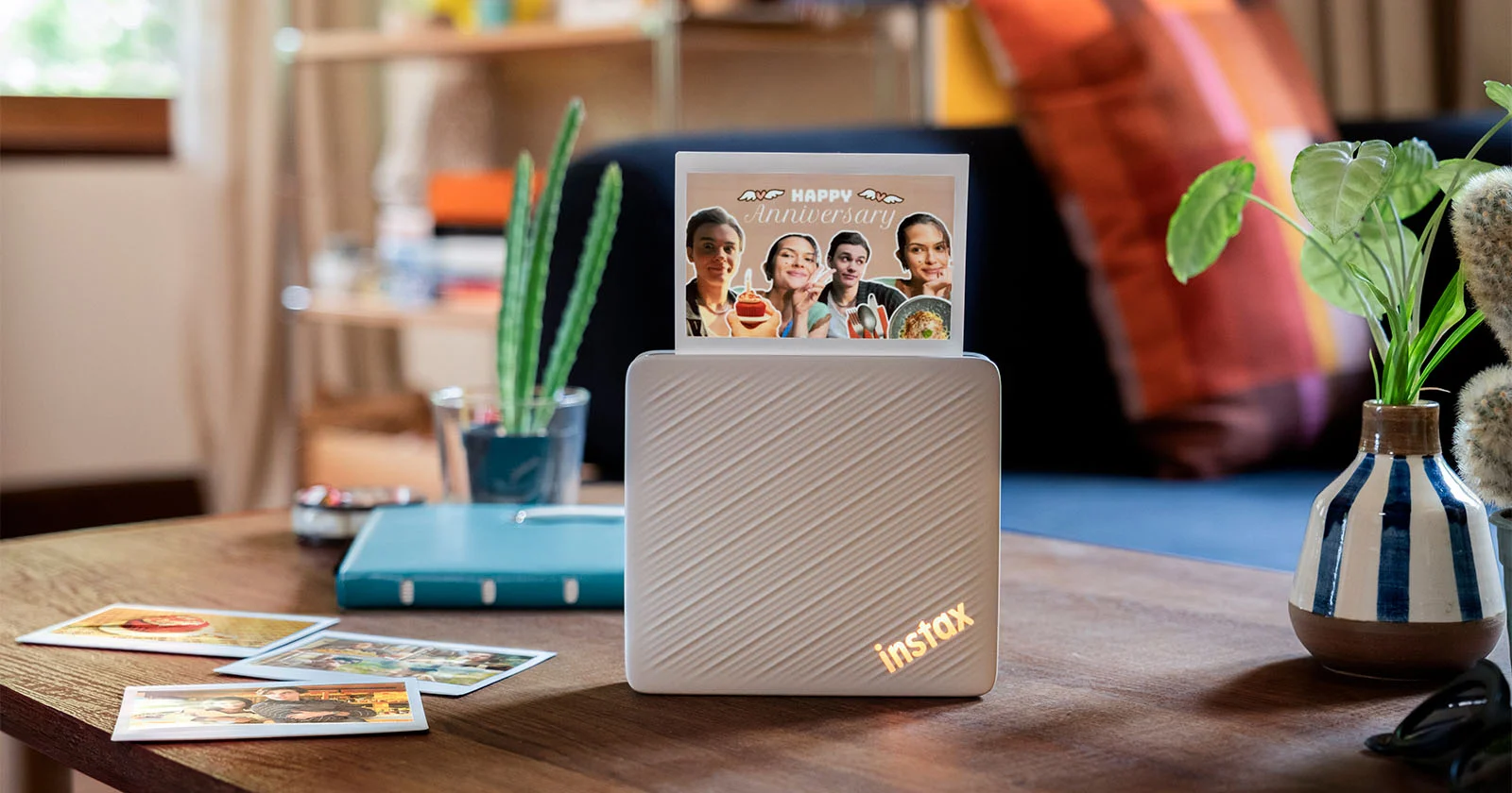 Бежевый принтер Instax Link Wide 2 с рельефным корпусом выдаёт карточку с коллажем из портретов, рядом на столе лежат готовые снимки