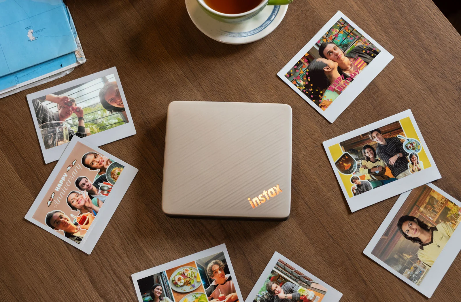 Вид сверху на принтер Instax Link Wide 2 на деревянном столе среди разложенных моментальных снимков широкого формата